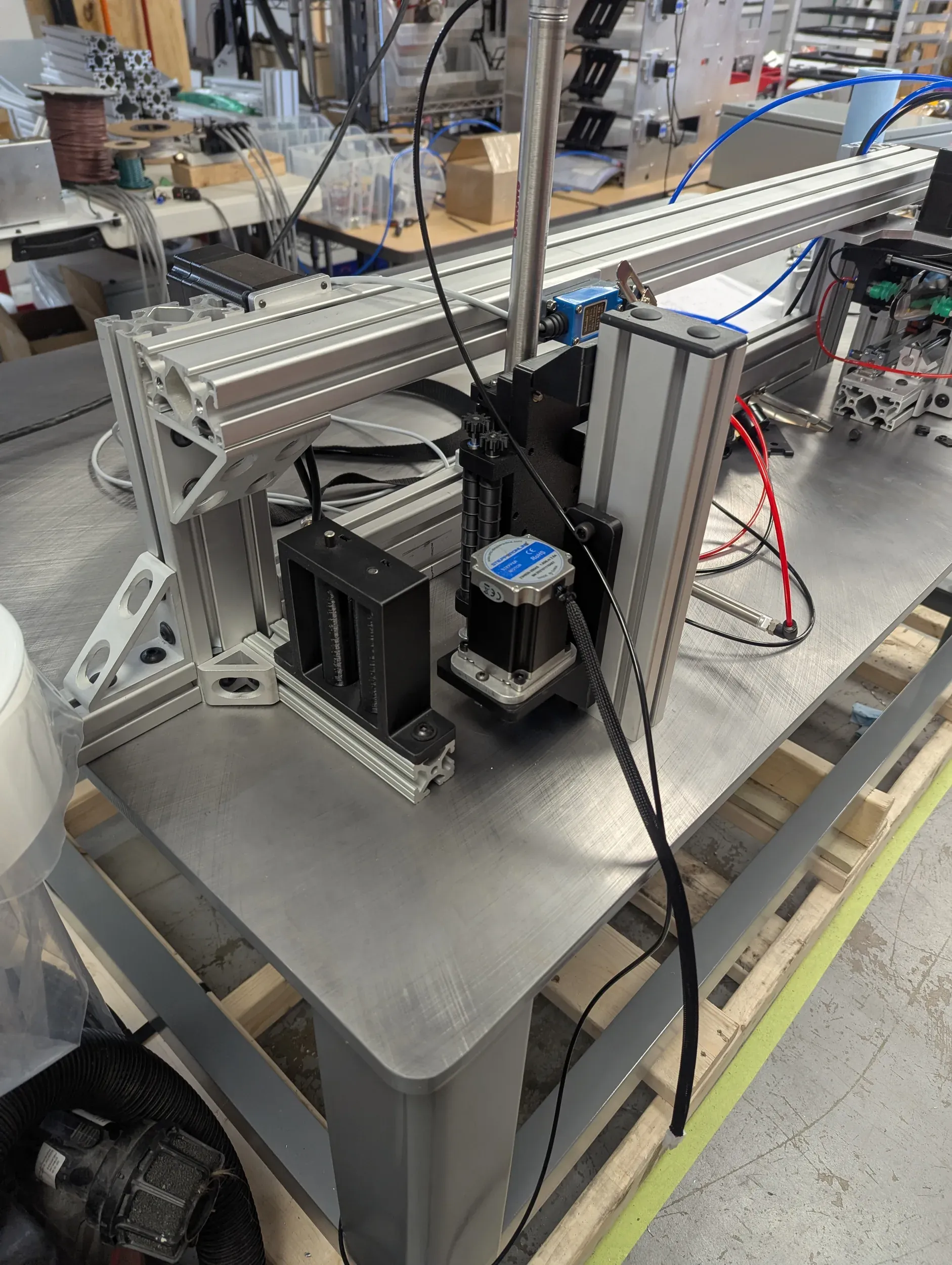 Custom machine in progress on a steel base: T-slot frame, stepper-driven axes, and wiring